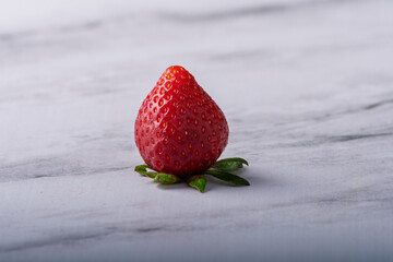Isolated strawberry with leaves facing downwards.