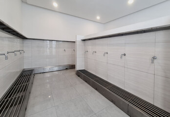 Modern ablution or wudu room with clean design, minimalist silver water taps and tiled walls before...