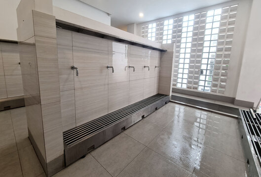 Modern ablution or wudu room with clean design, minimalist silver water taps and tiled walls before Islamic prayer preparation inside the mosque