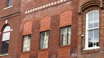 Windows on an old brick building in a small town with a security camera mounted on the facade