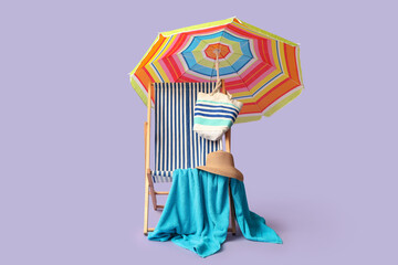 Striped deck chair with colorful umbrella and towel on lilac background © Pixel-Shot