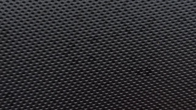 High-quality stop motion background featuring black synthetic leather with a decorative perforated dot pattern texture.