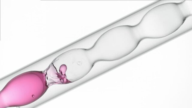 Air bubbles float through transparent rose liquid as it fills and drains from a bulb lab condenser on white bg | Strawberry distillate cosmetic product ingredient concept