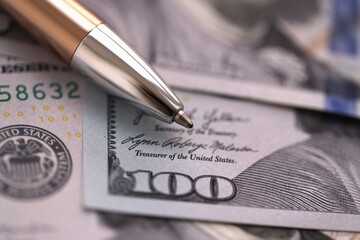 One hundred US dollar bills and silver pen close up. Concept of business calculating and accounting in United States