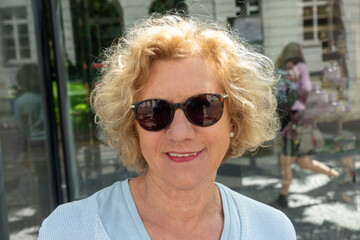 attractive senior woman with curly blonde hair and sunglasses