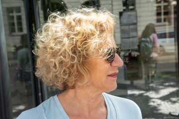 attractive senior woman with curly blonde hair and sunglasses