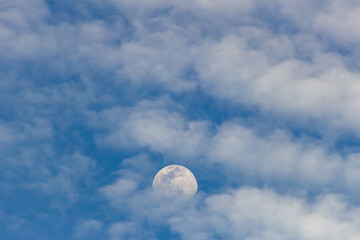 The moon in the blue sky and white clouds on a sunny day
