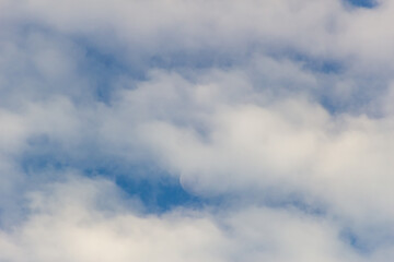The moon in the blue sky and white clouds on a sunny day