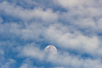 The moon in the blue sky and white clouds on a sunny day