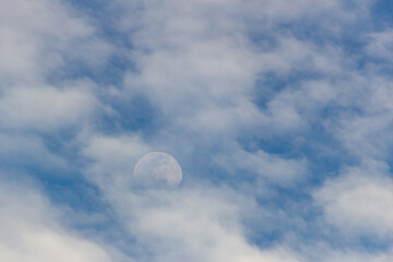 The moon in the blue sky and white clouds on a sunny day