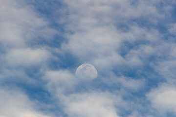 The moon in the blue sky and white clouds on a sunny day