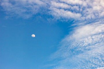 The moon in the blue sky and white clouds on a sunny day