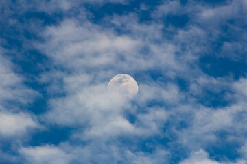 The moon in the blue sky and white clouds on a sunny day