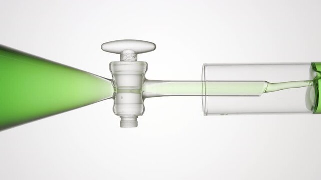 Green transparent fluid flows from separatory funnel through glass stopcock into test tube, filling it over light gray bg | Peppermint hydrosol skincare formulation development concept