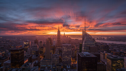Obraz premium Sunset skyline with glowing clouds and illuminated skyscraper silhouettes