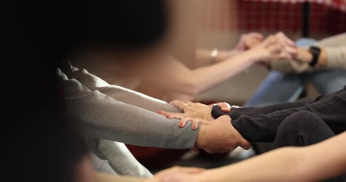 Multiple couples holding hands in partner yoga class, closeup