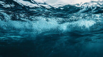 An underwater view of the ocean surface with bubbles and sunlight.