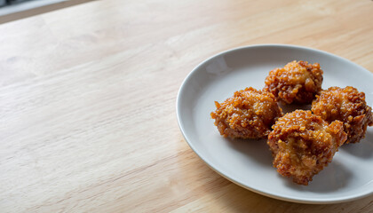 白い皿に盛られた鶏の唐揚げと木目テーブル