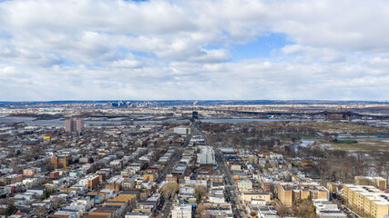 Aerial drone view over Lincoln Park in Jersey City with the Pulaski Skyway stretching across the horizon above the Hackensack River. Surrounding residential neighborhoods, open green space, and waterw