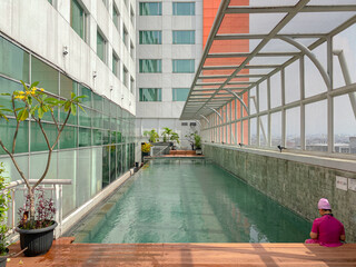 The atmosphere of the swimming pool on the hotel rooftop with a tall building wall beside it