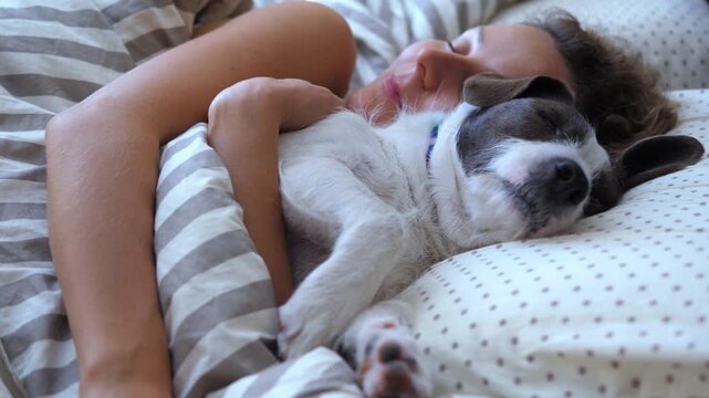 Peaceful moment of a young woman and her cute puppy sleeping together in a cozy bed. Intimate close up of a tender bond between a pet and its owner, sharing a tranquil rest in the morning