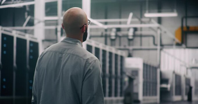 IT Specialist Conducting Physical Server Hall Inspection. Professional Engineer Walks Purposefully Through Massive Data Center Hall, Conducting Visual and Physical Inspection of Infrastructure Scale.