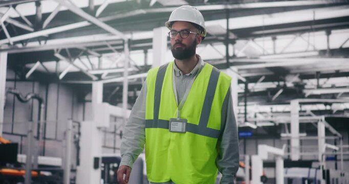 Engineer in Safety Vest Inspecting Production. Male Industrial Supervisor in Hard Hat Focused Inspecting Operations on IT Factory Floor. Industrial Safety, Production Management, Quality Control.