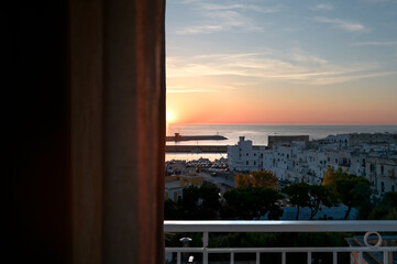 porto di monopoli all'alba visto da una finestra con una tenda