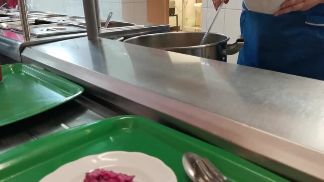 Customers slide trays along metal rails to select lunch dishes in a busy public dining room, showing a self-service cafeteria line and diverse meal options in high-quality 4k resolution.