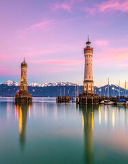 Obraz premium Twin Lighthouses Reflecting on Calm Water at Sunset