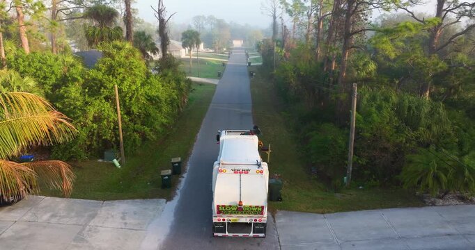 Garbage truck loading trash bin from the curb of American neighborhood.