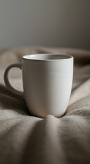 Fototapeta premium Warmth Within: Ceramic Mug on Textured Blanket, Soft Light.