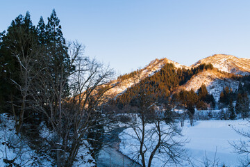 冬の山肌を照らす朝陽と雪景色の風景 / Morning sun lighting up the winter mountainside and snow landscape