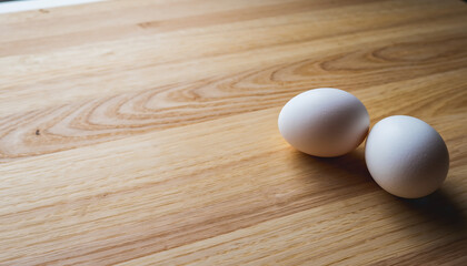 木目テーブルに置かれた2個の白い卵