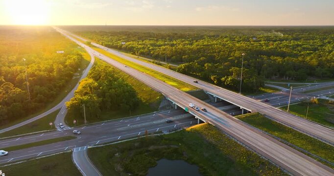 Wide multilane expressway crossroad with overpass ramps and flowing traffic in rural American landscape