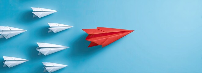 Red paper plane leads white ones against blue background