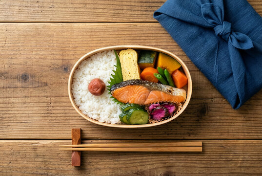 Top view of traditional Japanese magewappa bento box filled with white rice, grilled salmon, and vegetables