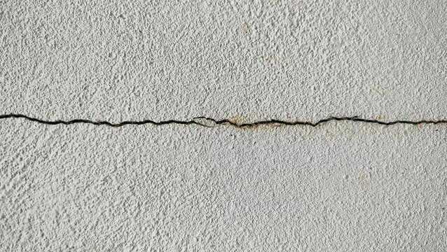 Gray concrete cracked house wall texture background. Cracks on the gray wall. That is not standard in construction. Crack in the concrete wall.