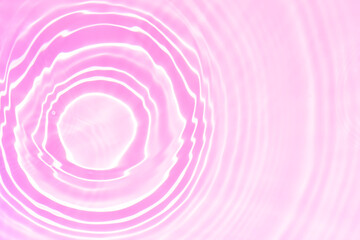 Pink water bubbles on the surface ripples. Defocus blurred transparent pink colored clear calm water surface texture with splash and bubbles. Water waves with shining pattern texture background