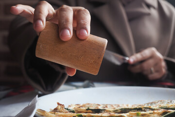 Using a wooden grinder to add seasoning on food