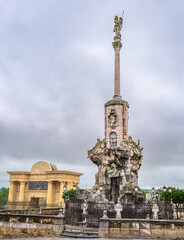 The Triumph of Saint Raphael monument stands before the historic Puerta del Puente gate under a cloudy sky in Cordoba, Andalusia, Spain.