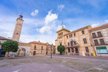 Historic town hall and clock tower on the main plaza of Consuegra in La Mancha Spain under a beautiful blue sky.