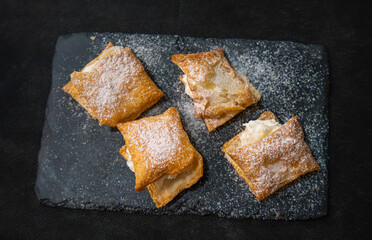 Delicious puff pastries filled with cream and dusted with sugar, served on a stone plate in Consuegra along the Don Quixote route in Spain.