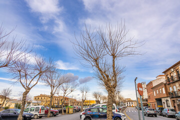 View of a local street and parking lot under a blue sky in Consuegra, a historic town on the Don Quixote route in Castilla La Mancha, Spain.