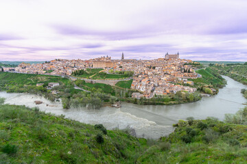 Scenic aerial view of Toledo Spain during spring twilight. The Rio Tajo river winds around the historic city center as a grand natural barrier.