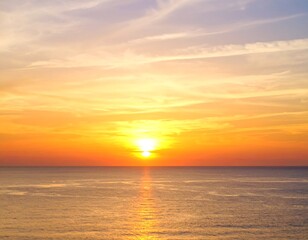 Obraz premium A mesmerizing scene of a sun setting over the ocean, painting the sky with vivid hues of orange, yellow, and blue