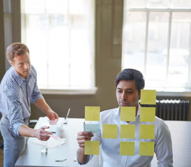 Men, meeting and reading sticky note in office for planning, schedule update and reminder. People, training and team brainstorming with strategy, moodboard timeline and problem solving for proposal