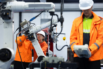 Fototapeta premium Engineer operating robot arm in electrical industry, Engineer working with robotic equipment machinery inside automated factory, Engineer operating robotic arm in electrical factory.