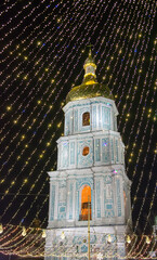Illuminated church bell tower with golden dome glowing at night covered by festive string lights creating sacred celebration mood and peaceful holiday atmosphere