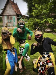Three dancers wearing colorful masks outdoors